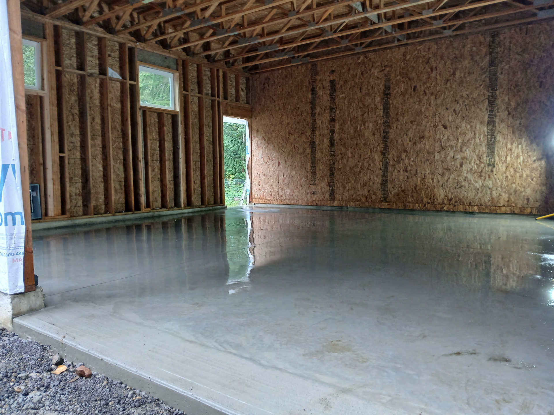 Freshly poured and finished concrete garage slab inside a framed structure